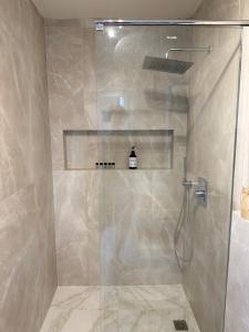 a shower with a glass door in a bathroom at Minimal Cream Apartment Pool-front in Paros in Parikia +36 photos