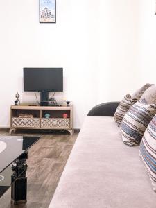a living room with a couch with a flat screen tv at Appartement charmant à deux pas de Rabat Tram et Gare à pied in Sale