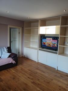 a living room with a tv and shelves at shiv's comfy apartment in Balnacart +17 photos