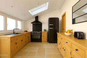 eine Küche mit einem schwarzen Kühlschrank und Holzschränken in der Unterkunft Villa Ô Dunes in Châtelaillon-Plage