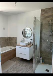 a bathroom with a sink and a tub and a mirror at Loue étage in Saint Pavace