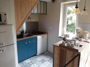 a kitchen with blue cabinets and a white refrigerator at La maison d'à côté in Montigny-sur-Loing