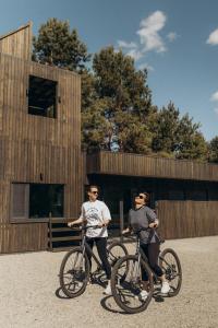 two men on bikes in front of a building at Будиночки для відпочинку ТРОХИ ДАЛІ in Dmitrenki
