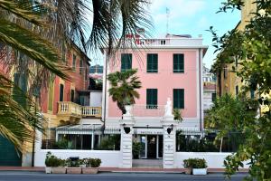 a pink building on a street with palm trees at Hotel Lido in Varazze