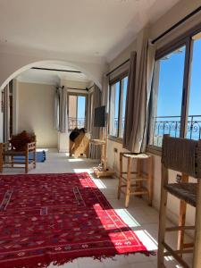 a living room with large windows and a red rug at SurfAppart Morocco in Tamraght Ouzdar