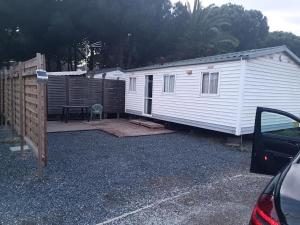 una piccola casa bianca con una recinzione e un tavolo di Camping Les Embruns N2 a Le Grau-dʼAgde