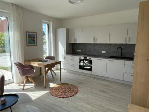 a kitchen with white cabinets and a wooden table at Appartement Löwenzahn in Spangenberg +26 photos