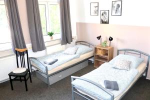 Un dormitorio con dos camas y una silla. en Sei hier Gast - Unterkunft Zimmer Klosterhof Aschersleben, en Aschersleben