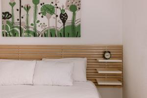 Bett mit einem Kopfteil aus Holz und einer Uhr darauf in der Unterkunft Apartamento junto al Recinto Ferial con garaje y aire acondicionado in Albacete