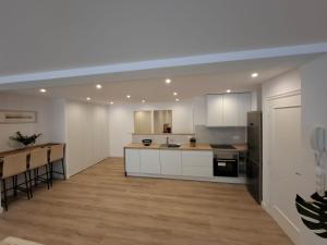 a large kitchen with white cabinets and a wooden floor at Apto Espectacular Plaza España in Ferrol
