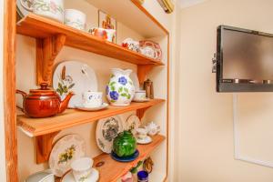 a room with wooden shelves with dishes and a tv at Harris Guest Accommodation in Oxford