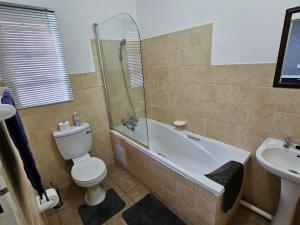 a bathroom with a toilet and a tub and a sink at Apartment Near Amajuba Mall in Newcastle