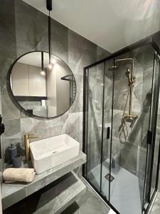 une salle de bain avec un lavabo et une douche avec un miroir dans l'établissement Apartamenty Kielce -CHOCOLATE, Rynek, Sienkiewicza, centrum, fv, targi, à Kielce