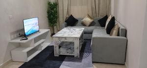 a living room with a couch and a table with a television at Relax nouvelle ville ibn batouta2 in Oulad Akkou +5 photos