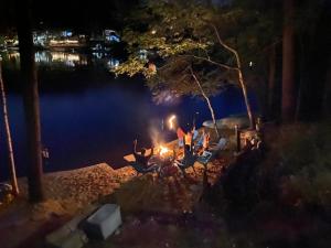 a group of people sitting around a bonfire at night at Lakefront Home-Stunning Views-Hot Tub, 3100 sqft! in Wakefield
