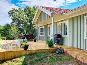 a small green house with a wooden deck at 8 person holiday home in ELLÖS in Ellos