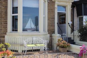 a white chair in front of a house with a sailboat in a window at The Ashley in Morecambe