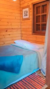 two beds in a wooden room with a window at Chalé nas Nuvens - Chalé Branco in Camanducaia
