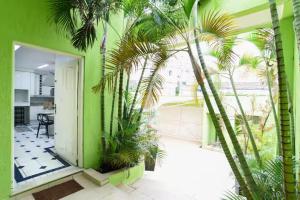a green building with palm trees in a room at Quarto privativo 5 minutos metrô com Piscina e churrasqueira in Sao Paulo