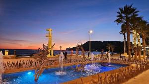 a fountain in front of the water with palm trees at Paradis Calpe in Calpe