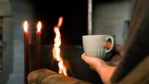 a person holding a coffee cup in front of fires at Sov Lodge in Vågåmo