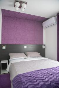 ein lila Schlafzimmer mit einem Bett mit einer lila Wand in der Unterkunft Sobe Novi grad in Osijek