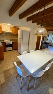 eine Küche mit einem weißen Tisch und Stühlen sowie einem Kühlschrank in der Unterkunft Cabañas Los Cipreses- Pellín in San Martín de los Andes