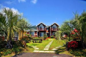 a large house with palm trees in front of it at Jubilee Chalet in Seogwipo