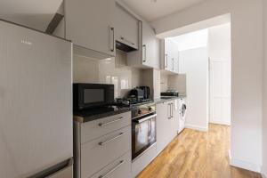 a kitchen with white cabinets and a tv on the counter at Spacious London Oasis in Welling
