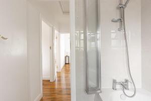 a glass shower in a white bathroom with a wooden floor at Spacious London Oasis in Welling