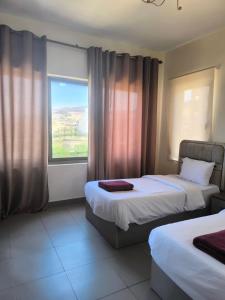 サワイマにあるE21 Samarah Resort Apartmentsのベッドが2つと窓があるホテルの部屋