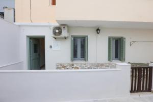 a white building with green windows and a fan at Terra Olivae Syros in Ermoupoli