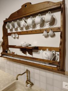 a rack of cups and saucers on a wall above a sink at Amorosa Dimora in Certaldo +25 photos