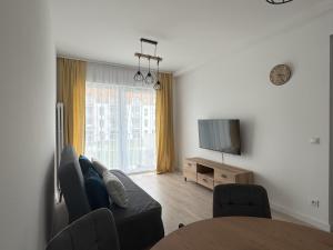 a living room with a couch and a television at Apartament Mika Let's Sea 73 Tuż przy plaży, klimatyzacja, basen in Gąski