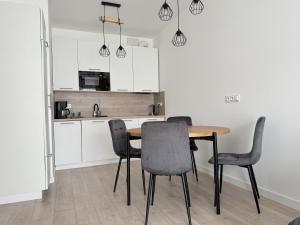 a kitchen with a dining room table and chairs at Apartament Mika Let's Sea 73 Tuż przy plaży, klimatyzacja, basen in Gąski