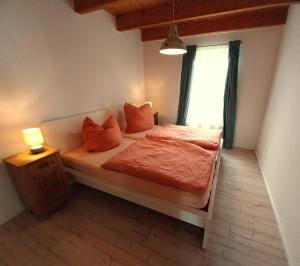 a bedroom with a bed with orange sheets and a window at Ferienhaus Dea in Krummhörn
