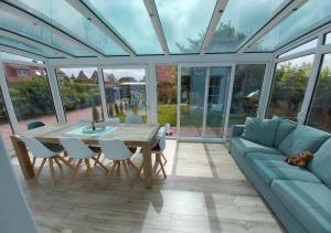 a conservatory with a table and chairs and a couch at Ferienhaus Dea in Krummhörn
