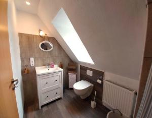 a bathroom with a toilet and a sink and a skylight at Ferienhaus Dea in Krummhörn +32 photos