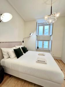 a bedroom with a large white bed with a chandelier at Santa Justa Bedrooms in Lisbon