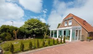 a brick house with a conservatory on a lawn at Ferienhaus Dea in Krummhörn