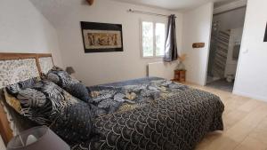 a bedroom with a bed with a black and white comforter at Gîte Elendil - Esprit Champêtre in Chambon
