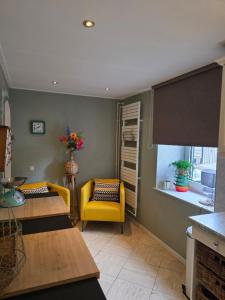 a living room with two tables and a yellow chair at Boerderijwoning in Maastricht