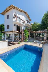 a villa with a swimming pool in front of a house at Casa Búzios Ama in Búzios