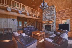 a living room with leather furniture and a stone fireplace at Large Private Home, Pool, Hot Tub, Sauna, Games in Mille-Isles