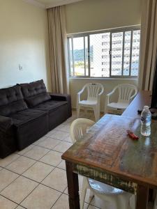 un salon avec un canapé, une table et des chaises dans l'établissement Apartamento centro de Peruíbe, à Peruíbe