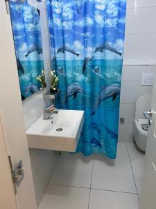 ヴェリポジェにあるPelinku Apartmentの洗面台とイルカのシャワーカーテンを備えたバスルーム