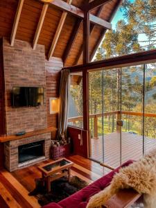a living room with a fireplace and a large window at Pousada Vale da Neve in Urubici