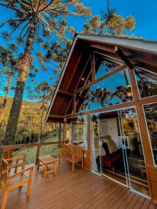 a house with a deck with a large glass window at Pousada Vale da Neve in Urubici