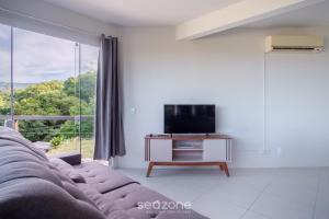 a living room with a couch and a tv at Casa c/ Vista Lagoa e Churrasqueira CTM0000 in Siriú