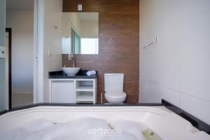 a bathroom with a tub with a toilet and a sink at Casa c/ Vista Lagoa e Churrasqueira CTM0000 in Siriú +19 photos
